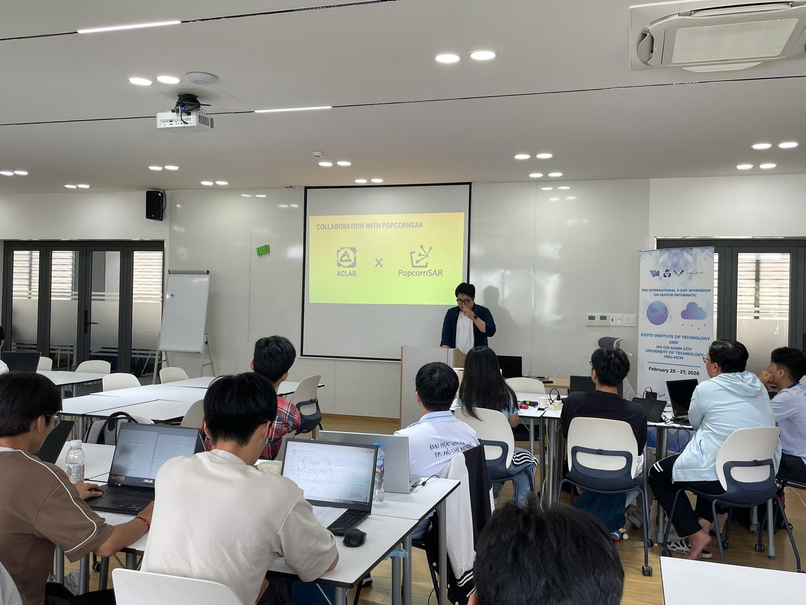 HCMUT 강의실에서 진행된 워크숍. 화면에 ACLAB 과 PopcornSAR 로고가 함께 떠 있다.